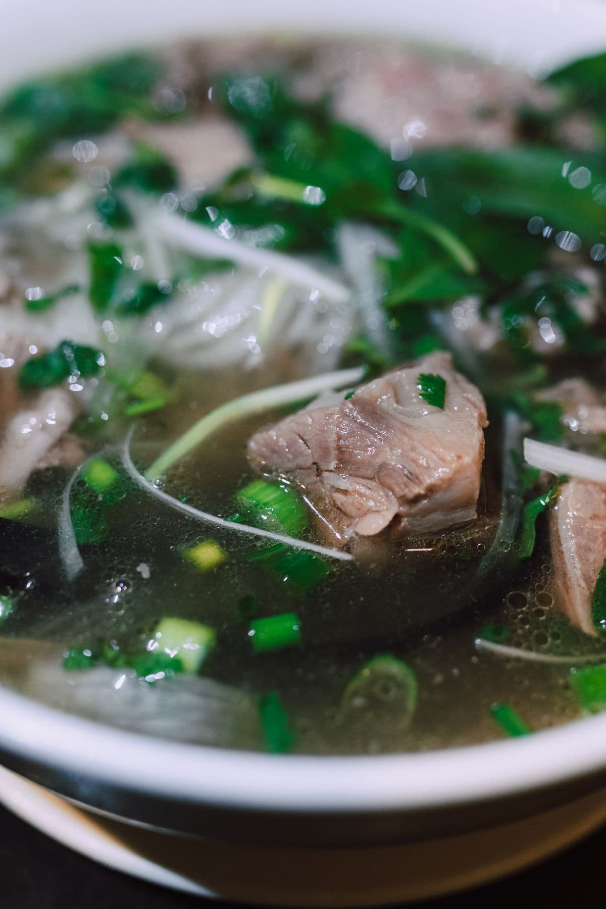 Phở Việt Nam v keramickej mise s bylinkami a limetkou po strane.
